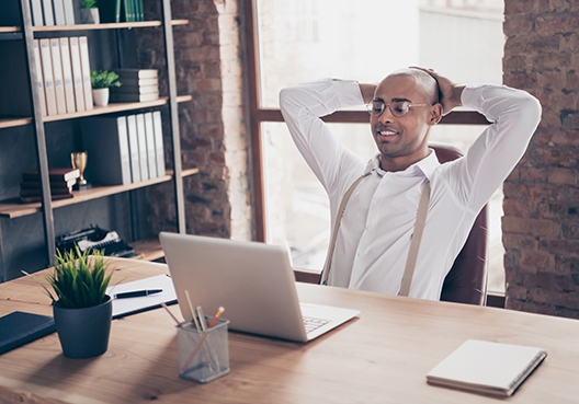 man looking relaxed siting behind his desk