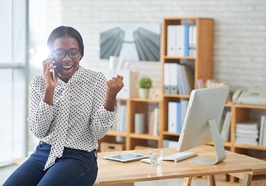 Woman sitting on her desk talking on her cell phone