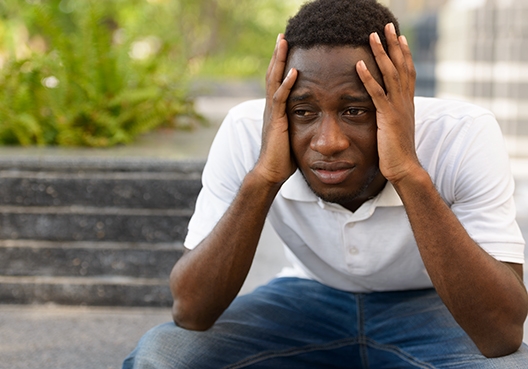 guy sitting on a step with his head in his hands looking worried