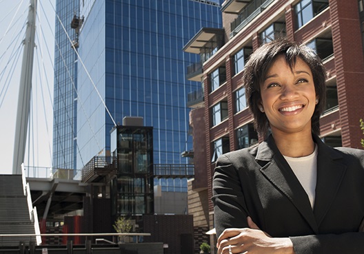 Woman standing in front of an office building with her arms crossed, smiling