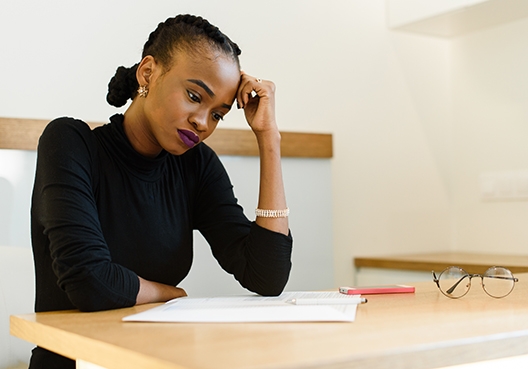 young lady sitting at a table looking worriedly at the paper in front of her