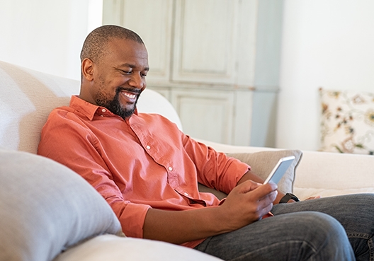 man sitting on his couch looking at his phone