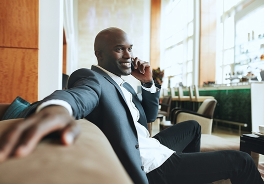 A young man wearing a suit and tie makes a phone call from his hotel.