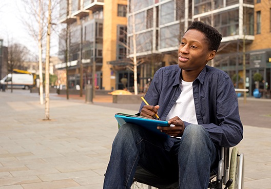 man sitting in a wheelchair with his tablet on his lap