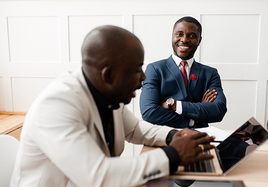 Two men having a laughing while the one man is looking at his laptop