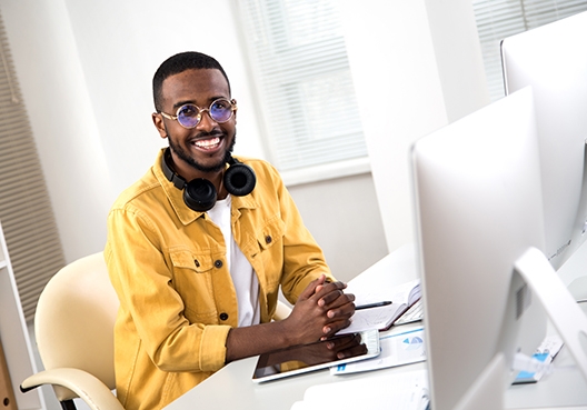 man smiling at the camera while his fingers are on his keyboard
