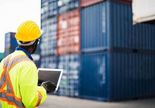 A worker making notes in front of cargo containers