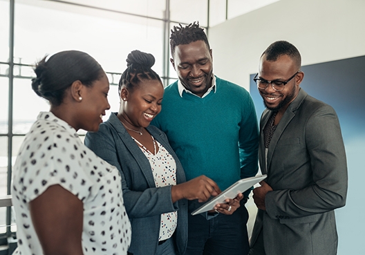 Group of people in a huddle looking at a tablet